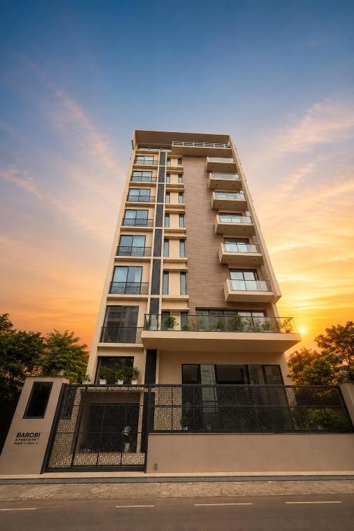 a tall apartment building with a sunset in the background at Barobi Apartment in Solpur