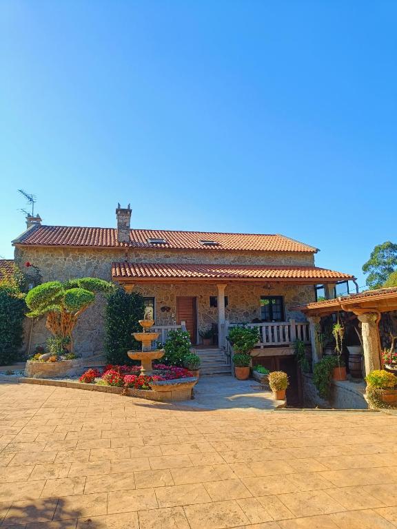 a house with a porch and flowers in front of it at Casa Ameneiros in Sanxenxo