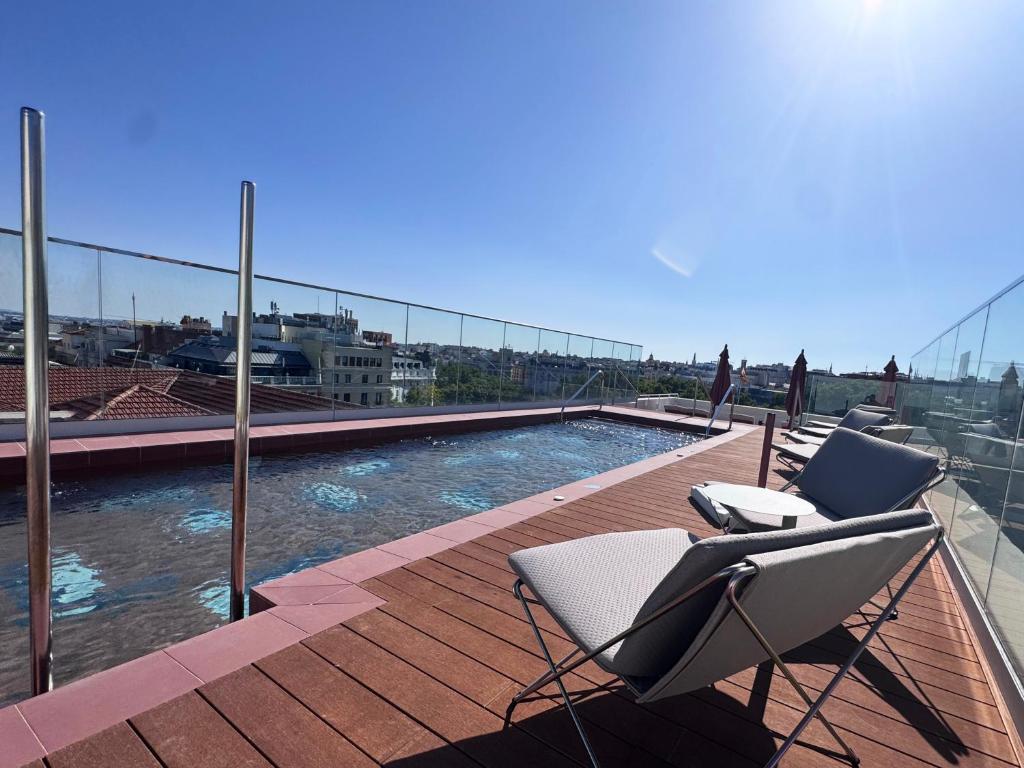 a deck with two chairs and a pool on a building at Mercer Madrid in Madrid