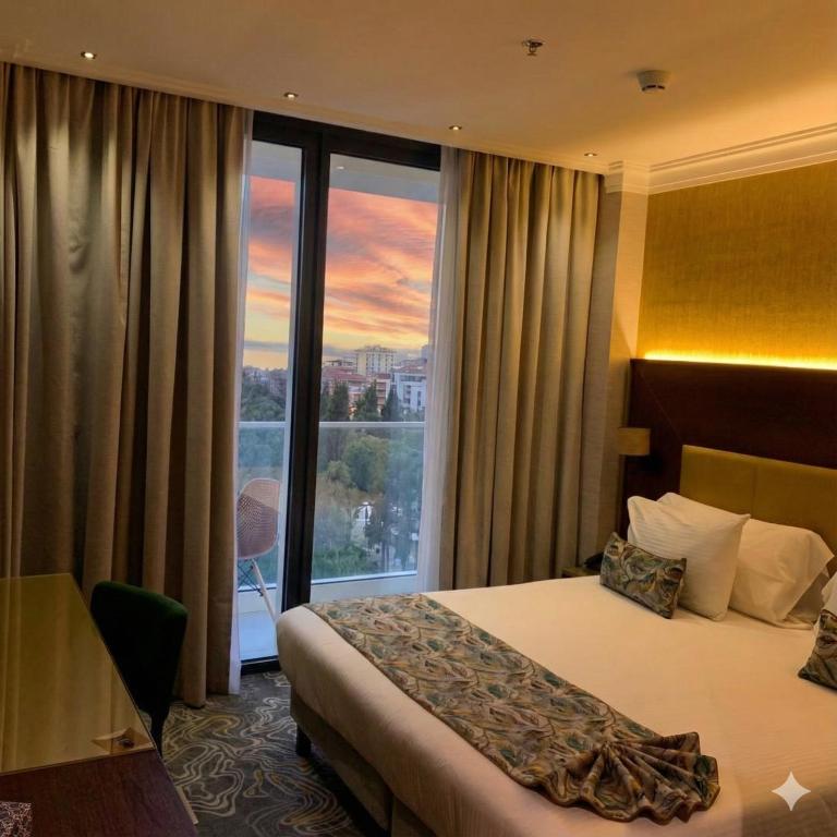 a hotel room with a bed and a large window at Hôtel Saint Eugène in Bab el Oued