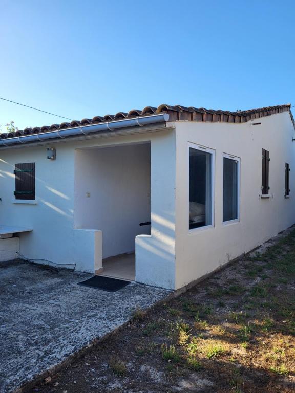 a white house with a garage and a yard at Le Refuge du Phare in Saint-Vivien-de-Médoc