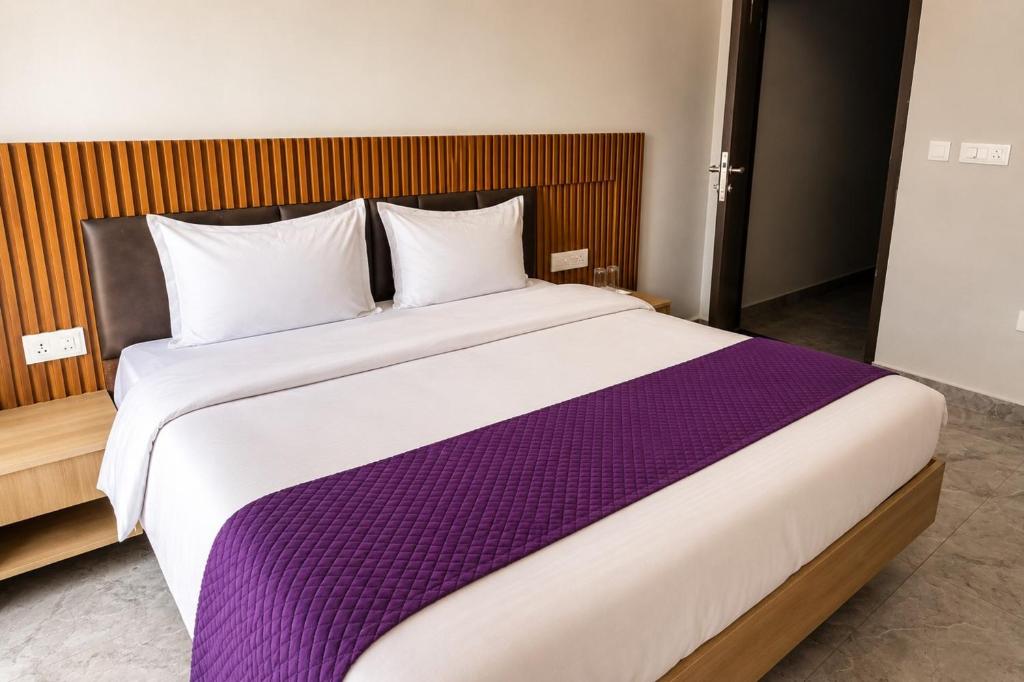a bedroom with a large bed with a purple blanket at Hotel Elev11 Near Ambala Chandigarh Highway, Zirakpur in Zirakpur