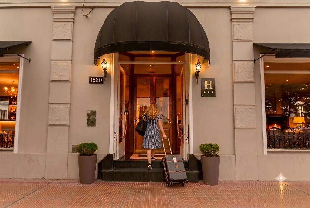 a woman walking out of a building with her luggage at Hotel Francia in Tandil