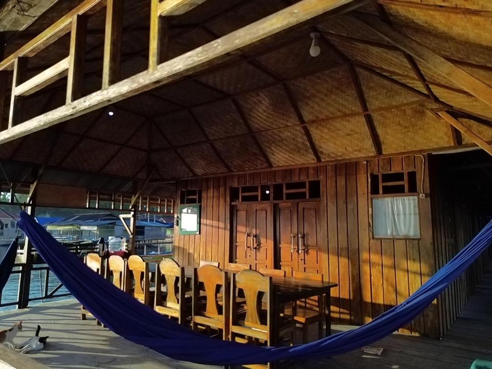 a hammock in a building with a table and chairs at Losmen Togean Wisata in Pulau Togian