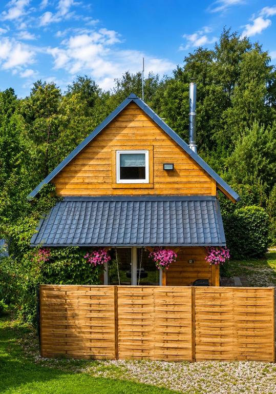 a house with a black roof on top of a fence at Śledziowy Domek 