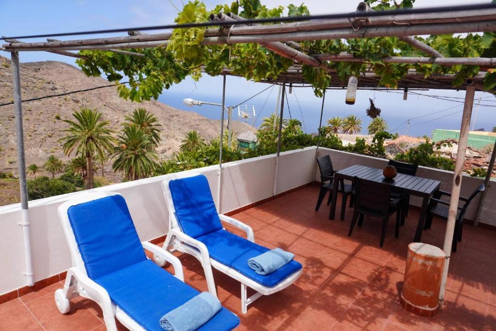 a balcony with blue chairs and a table with a view at Casa Argelio in Alojera