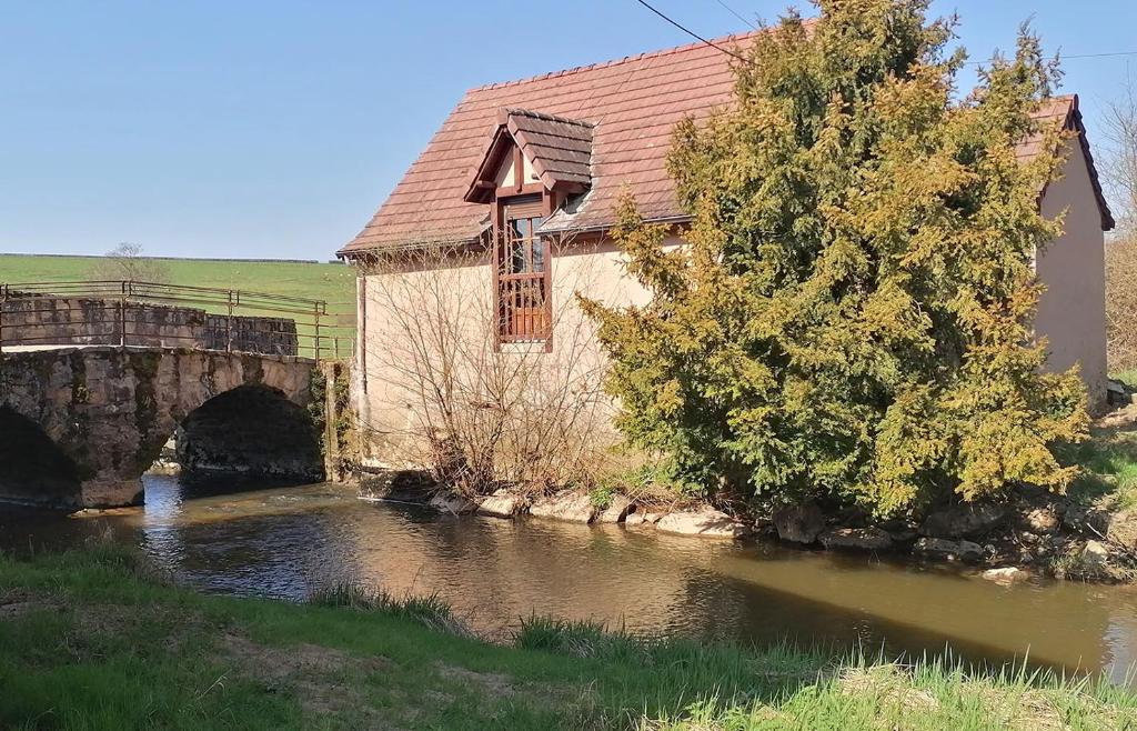 a building next to a river with a bridge at Gite Fée Grenouille in Martigny-le-Comte