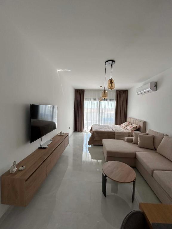 a living room with a couch and a tv at New Luxury Studio In Caesar Resort & Spa in Dherinia