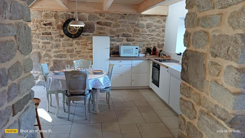 a kitchen with a table and a stone wall at Ty Penty in Riantec