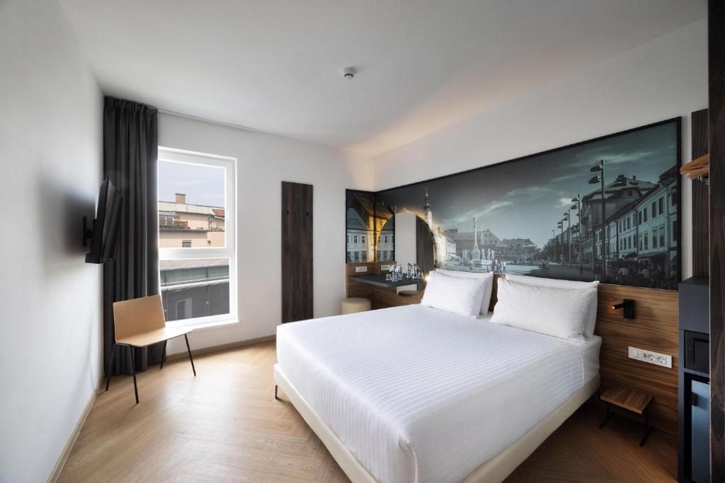 a bedroom with a white bed and a large window at B&B Hotel Maribor in Maribor