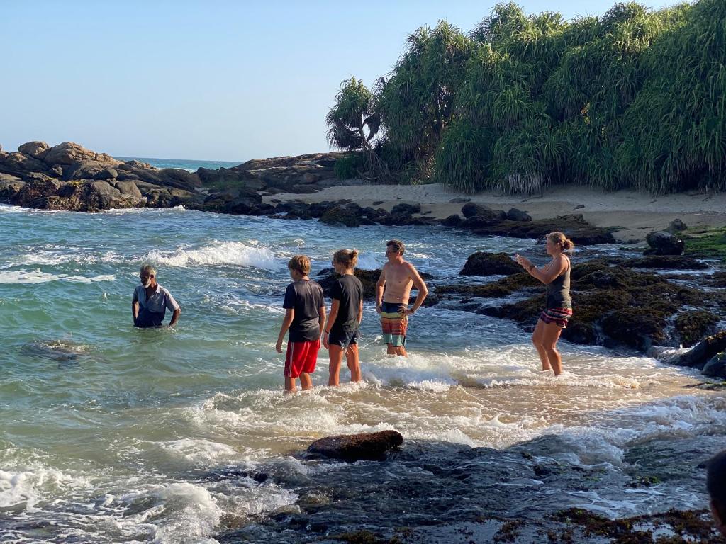 a group of people standing in the water on a beach at See Turtle Villa in Tangalle