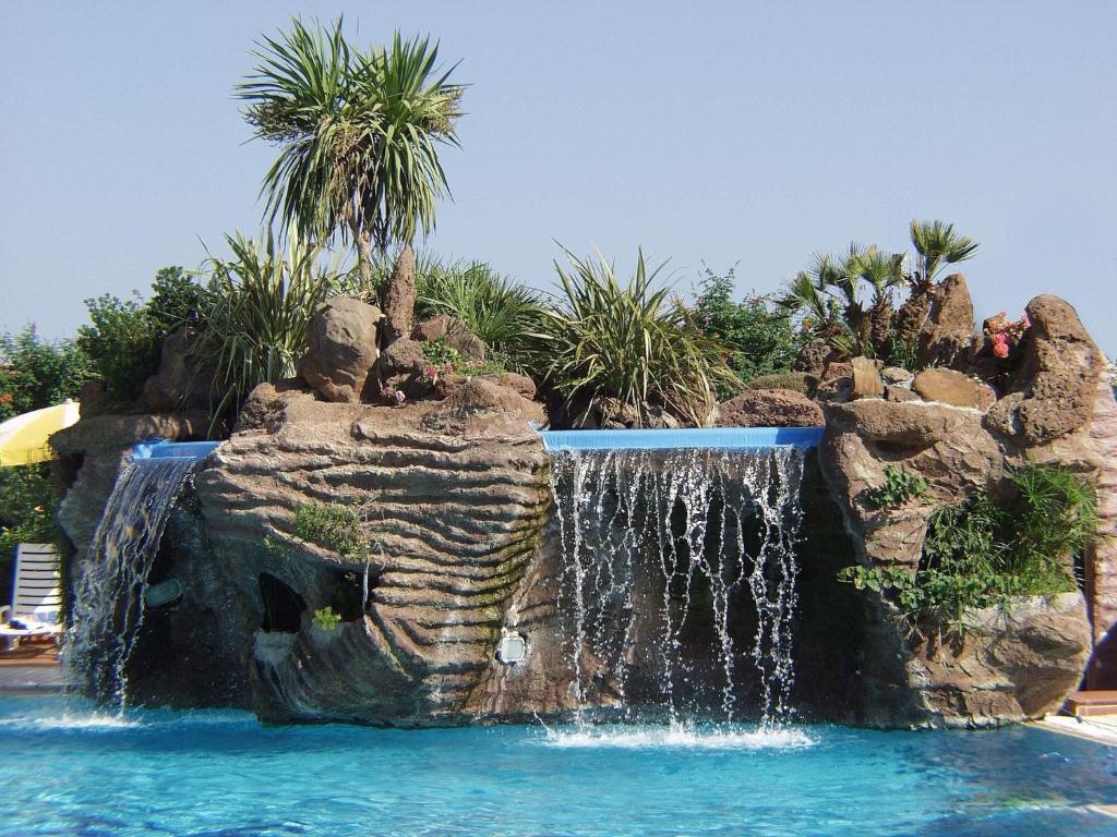 a waterfall in the middle of a pool at a resort at Le Residence del Golfo Orosei in Orosei