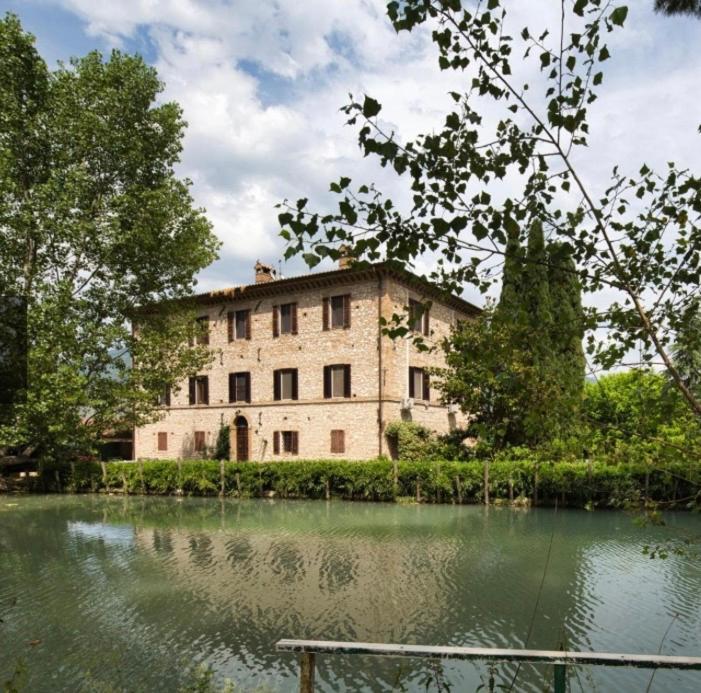 an old building sitting next to a body of water at Casale Antico Mulino in Beroide