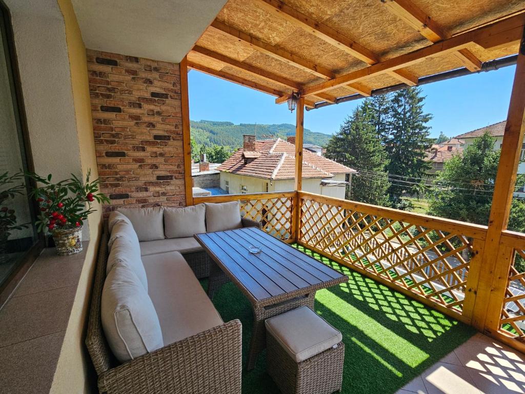 a patio with a couch and a table on a balcony at къща Чипровка in Chiprovtsi