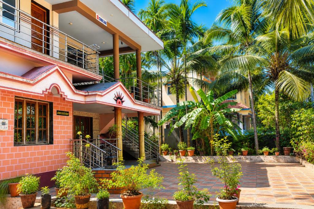 a pink building with palm trees in front of it at Omkar Homestay - Honavar in Kāsarkod