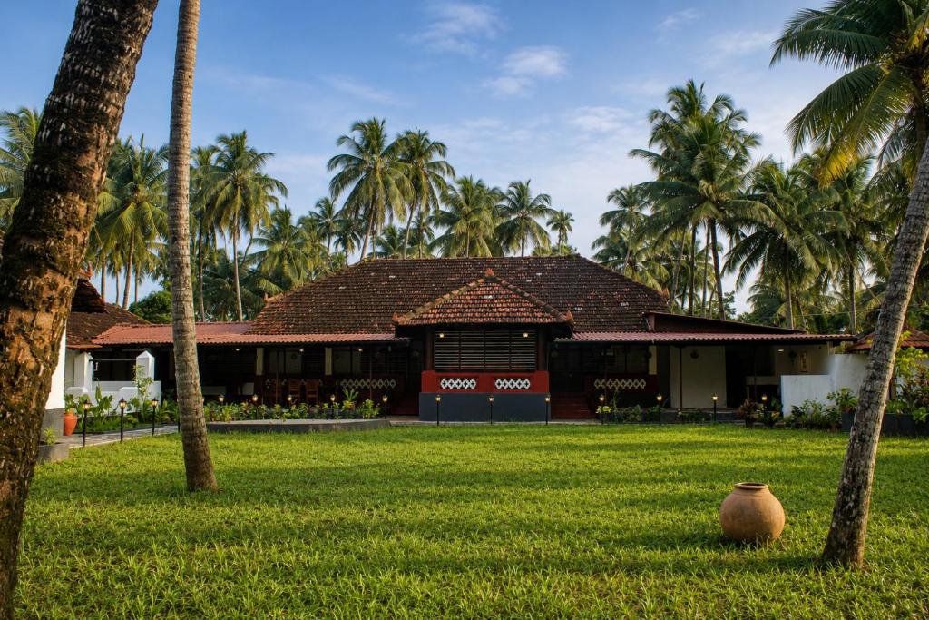 a building with palm trees and a vase in the grass at Udupi River Inn in Kalyānpur