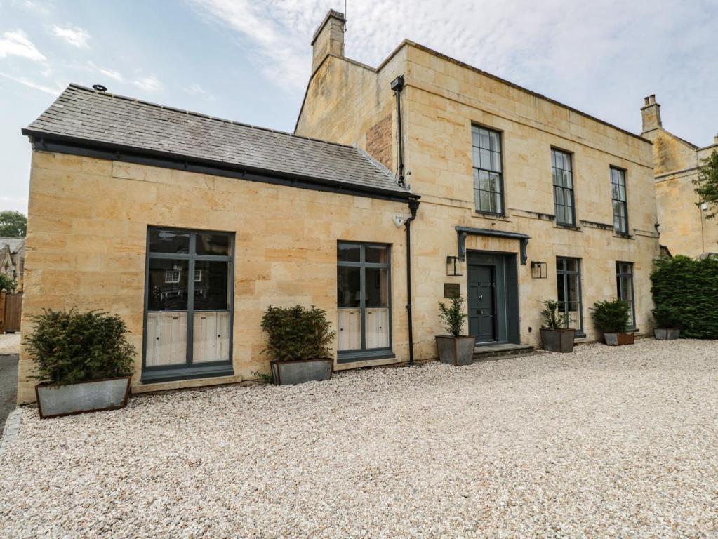 an old stone building with doors and potted plants at Cotswold House in Moreton in Marsh