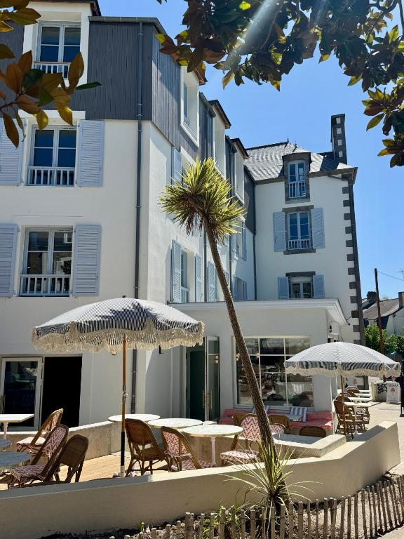 a patio with tables and umbrellas in front of a building at Hotel Saint-Enogat in Dinard