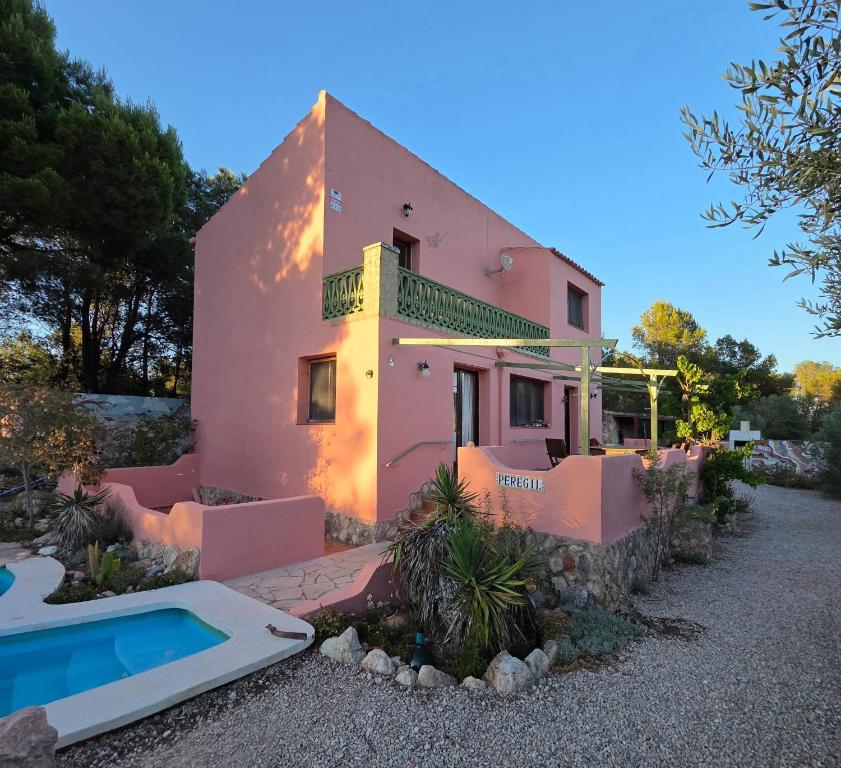 a pink house with a swimming pool in front of it at Casa Peregil in Perelló