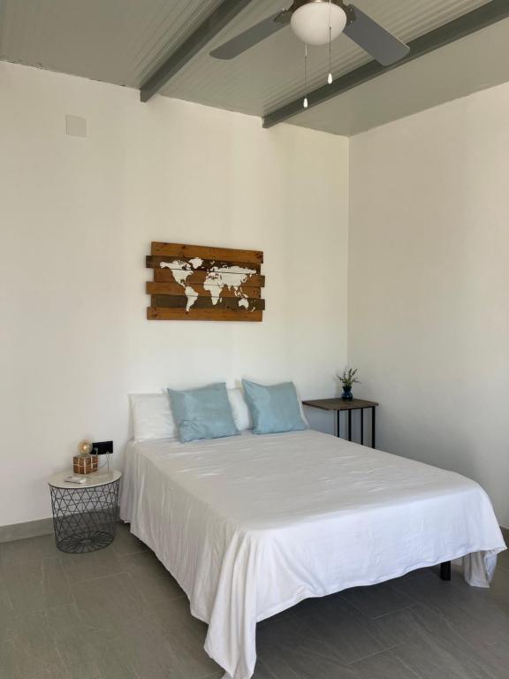 a white bedroom with a white bed with blue pillows at Habitación Manzanilla in Sanlúcar de Barrameda