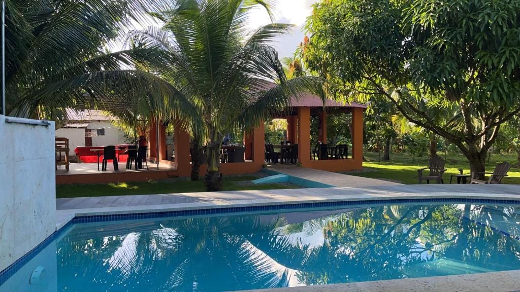a swimming pool with a gazebo and palm trees at Rancho Doña Rita in Higuey