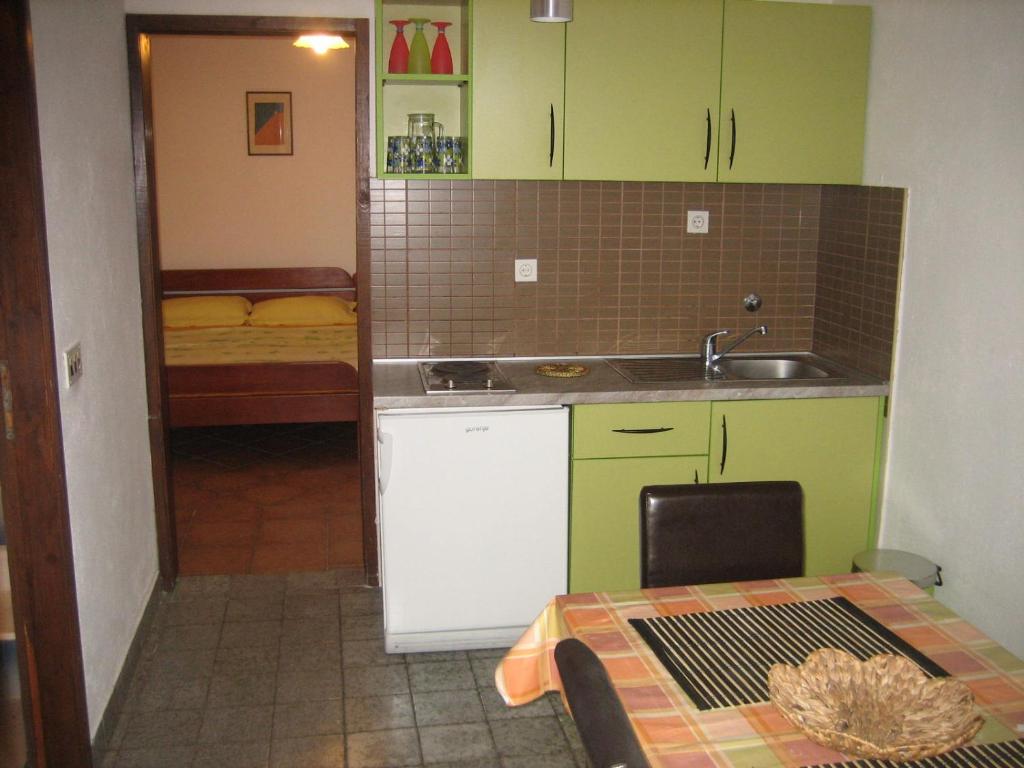 a kitchen with green cabinets and a sink and a table at Mitko Apartments in Budva
