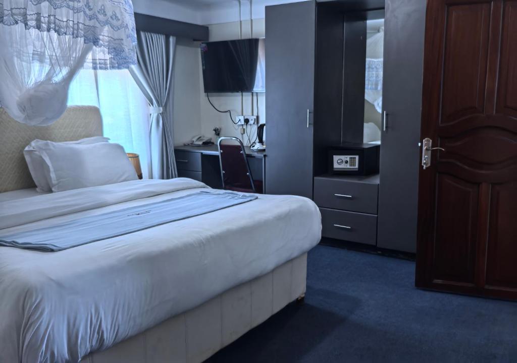 a bedroom with a bed and a desk and a window at Kaa Highway Hotel in Mukono