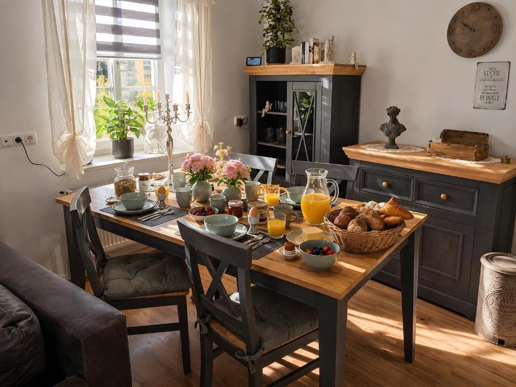 a dining room table with breakfast foods and orange juice at Rosenzauber Seeromantik "Kramer" in Weißenstadt