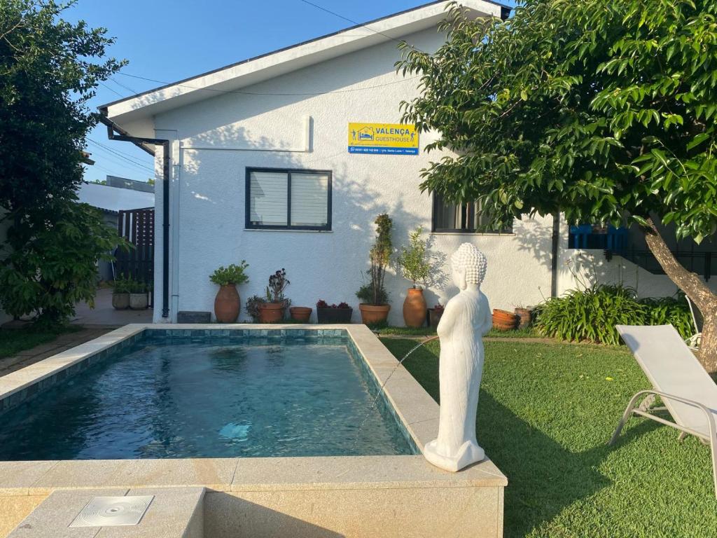 a swimming pool with a statue next to a house at Valença Guesthouse in Valença
