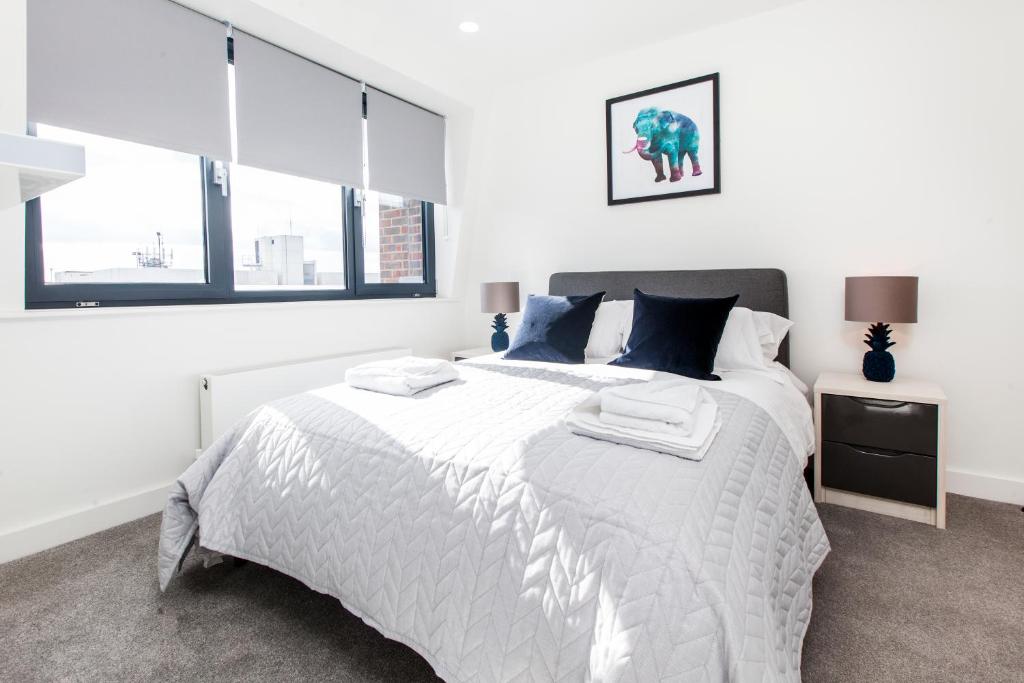 ein weißes Schlafzimmer mit einem großen Bett mit blauen Kissen in der Unterkunft City Stay Apartments - Platform Bedford in Bedford