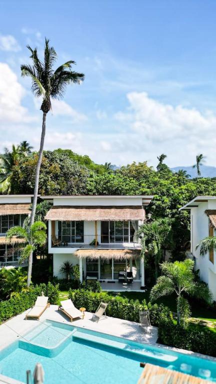 a house with a swimming pool and a palm tree at Beachfront Dream in Ban Tai in Ban Tai
