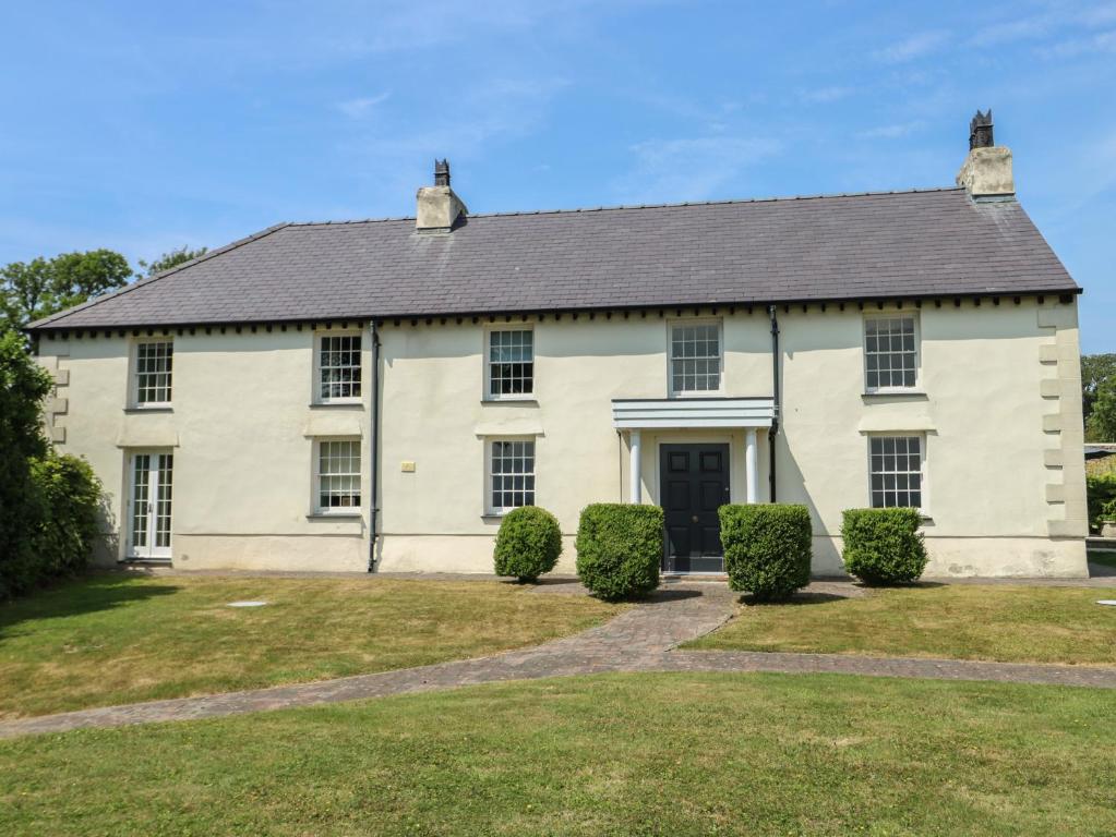 a large white house with bushes in front of it at Clynnog House in Dwyran