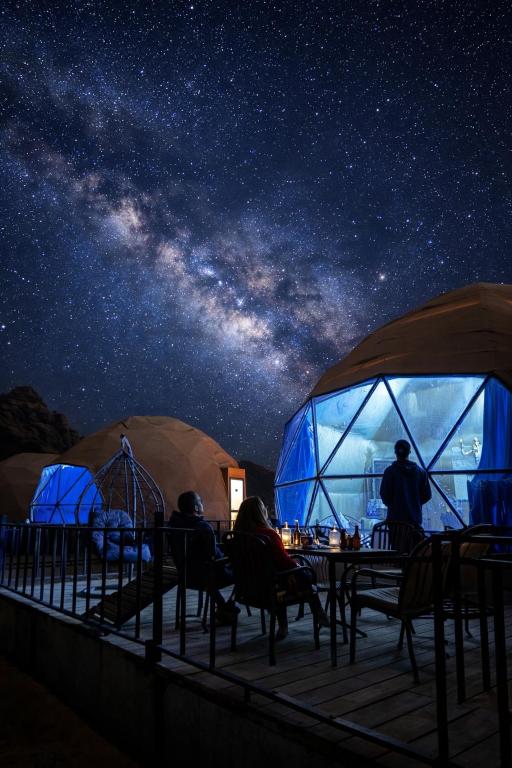 a group of people sitting at a table under a starry sky at Wadi rum bubble camp in Wadi Musa