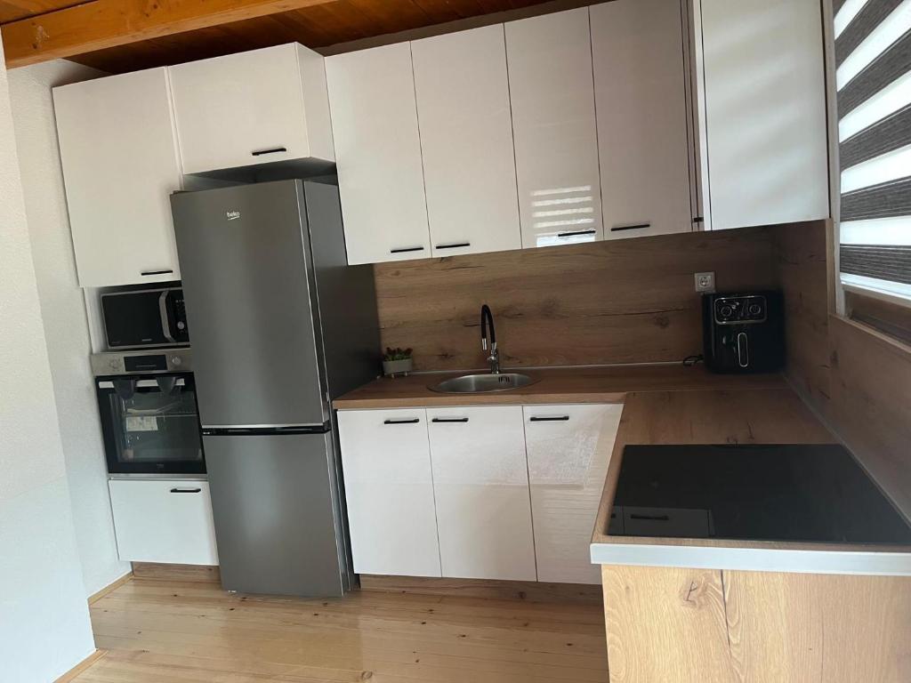 a kitchen with white cabinets and a stainless steel refrigerator at Planinska Idila in Vareš