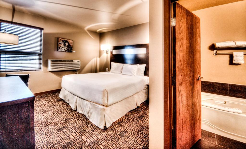 um quarto de hotel com uma cama e uma casa de banho em Podollan Inn & Spa - Grande Prairie em Grande Prairie