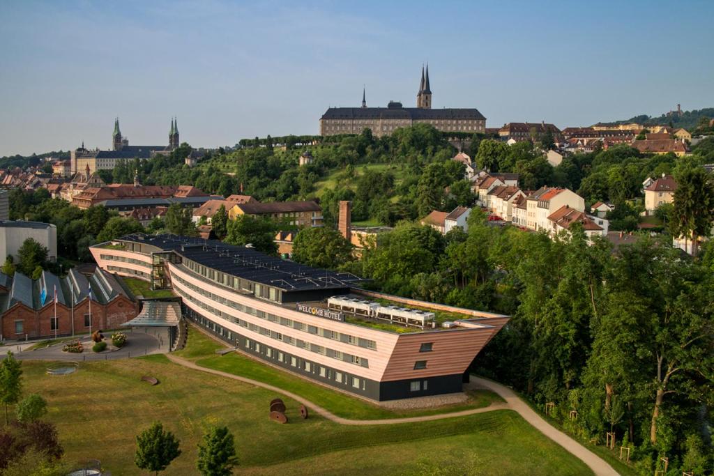 a building on a hill with a town in the background at Welcome Kongress Hotel Bamberg in Bamberg