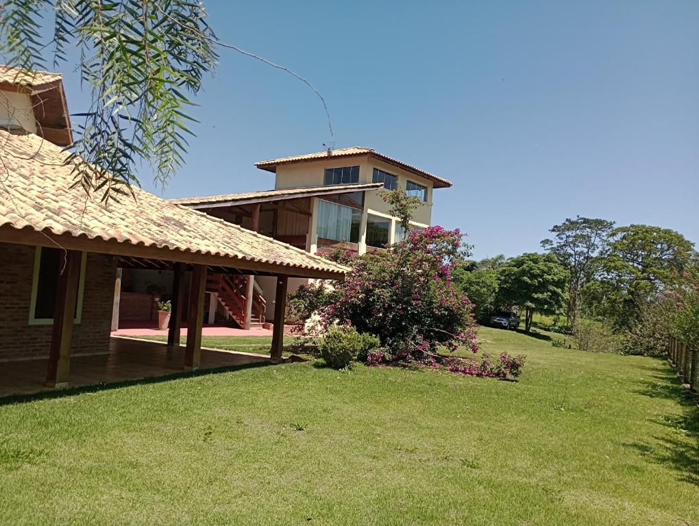 a house with a grass yard with a building in the background at Refúgio do Jaguari in Piracaia
