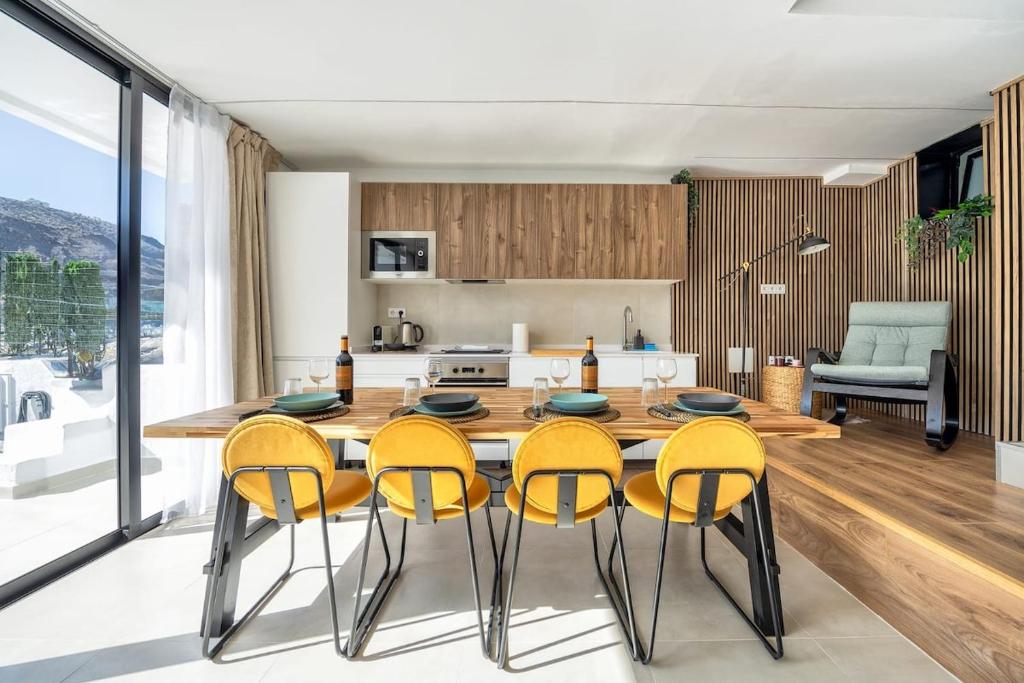 a kitchen with a wooden table and yellow chairs at Casa Arizona Central Duplex Puerto Rico GC in Mogán
