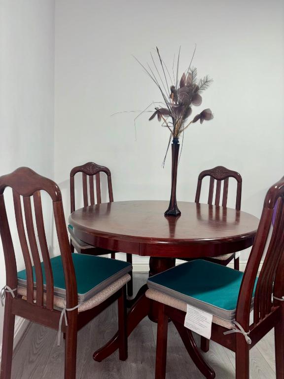 a wooden table with two chairs and a vase with flowers at HomesRentals in Dudley