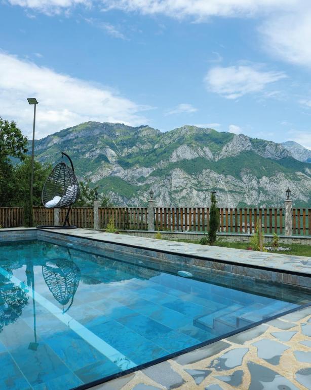 a swimming pool with a chair and mountains in the background at Villa Bushati in Tropojë