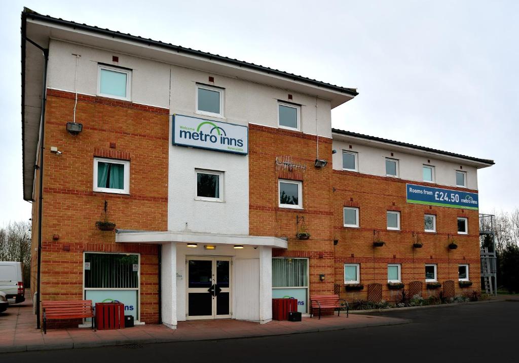 un gran edificio de ladrillo con bancos delante en Metro Inns Newcastle en Newcastle