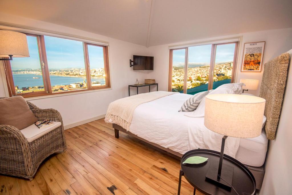 a bedroom with a bed and a chair and windows at Departamento San Enrique in Valparaíso