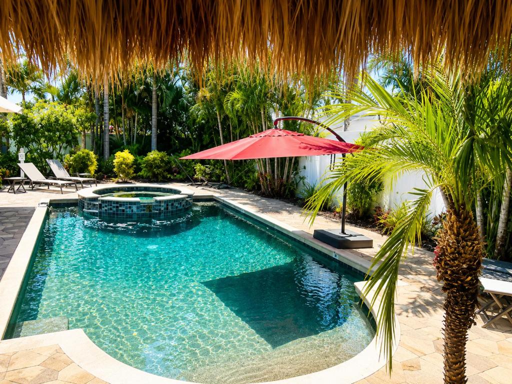 a swimming pool with a red umbrella and a palm tree at Tropical Oasis 10th in Bradenton