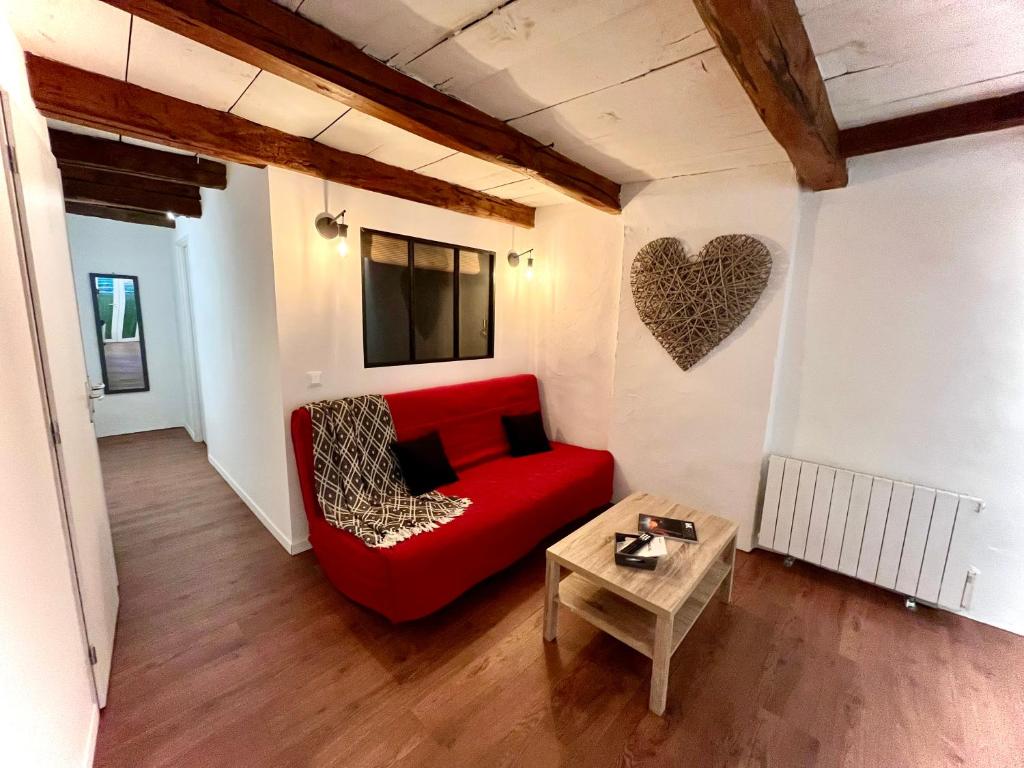a living room with a red couch and a heart on the wall at Suite Église in Veynes