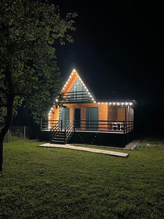 a cabin with lights on the side of it at night at Kaniore Cottage in Martvili