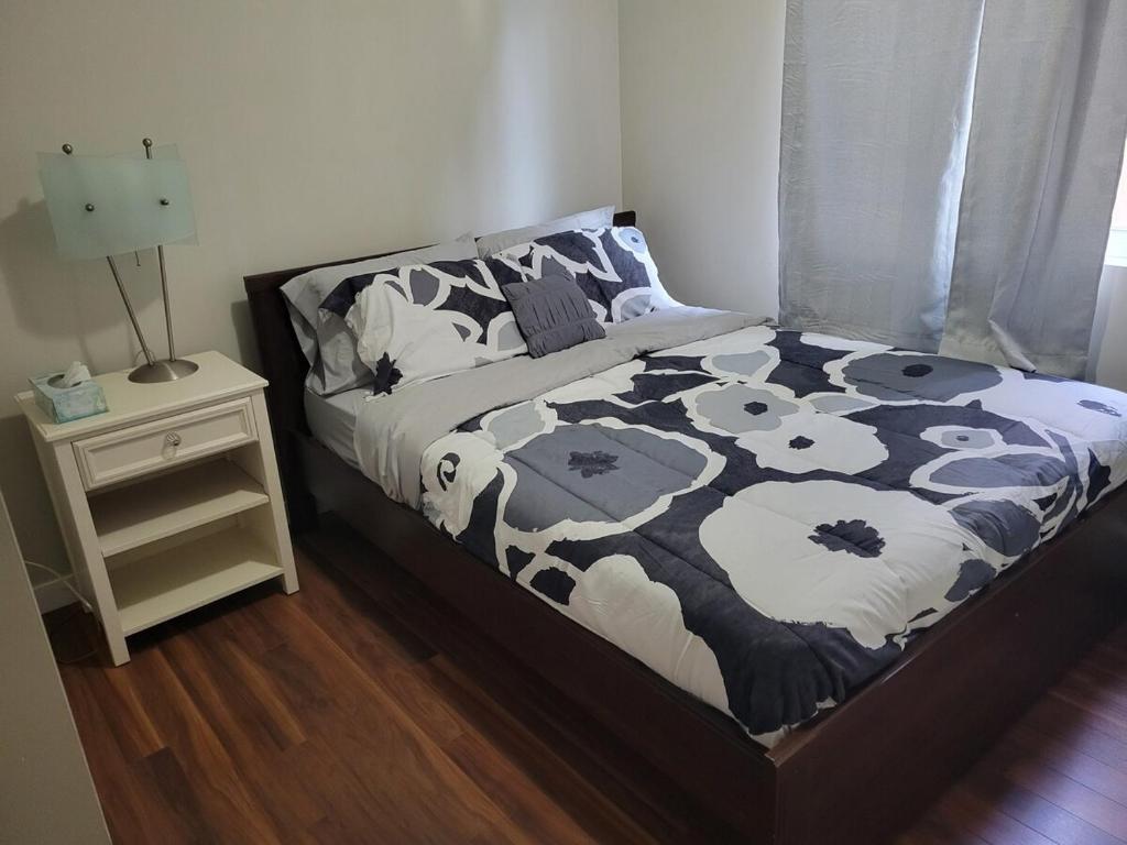 a bed with a black and white blanket and a night stand at Private 2 bedroom suite close to everything! in Maple Ridge