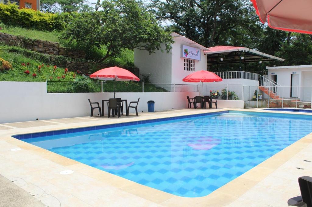 a swimming pool with two tables and umbrellas at Finca Campestre el Paraíso Resort Hotel en Mesitas in El Colegio