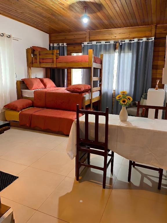 a bedroom with two bunk beds and a table and chair at Pousada Canto Gira Sol Penha SC Estúdio Sol 5 Min do Beto Carrero in Penha