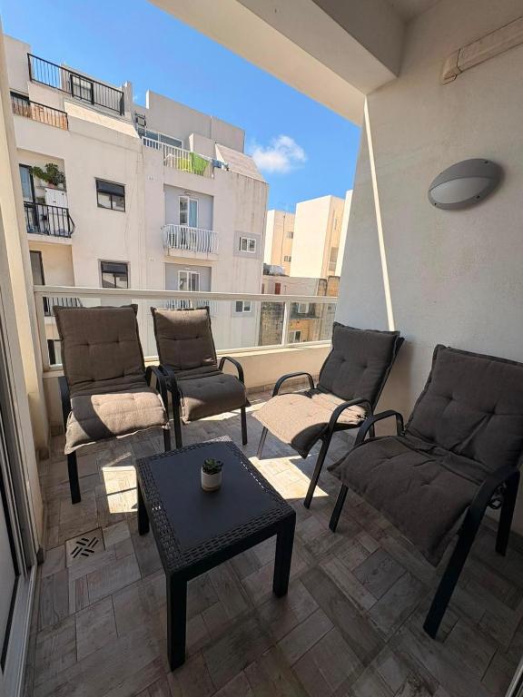 a living room with chairs and a table on a balcony at The Bright Bridge, Near Sliema with AC in Il-Gżira