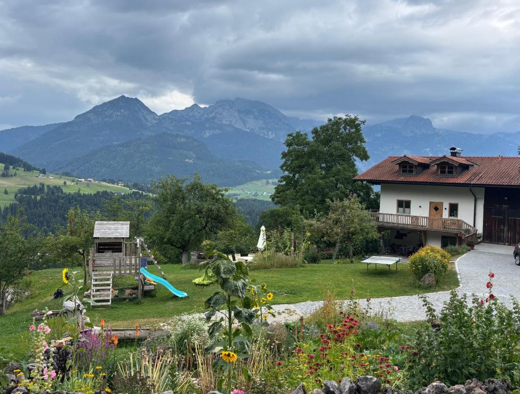 a house and a playground with mountains in the background at Hörndlhof in Abtenau